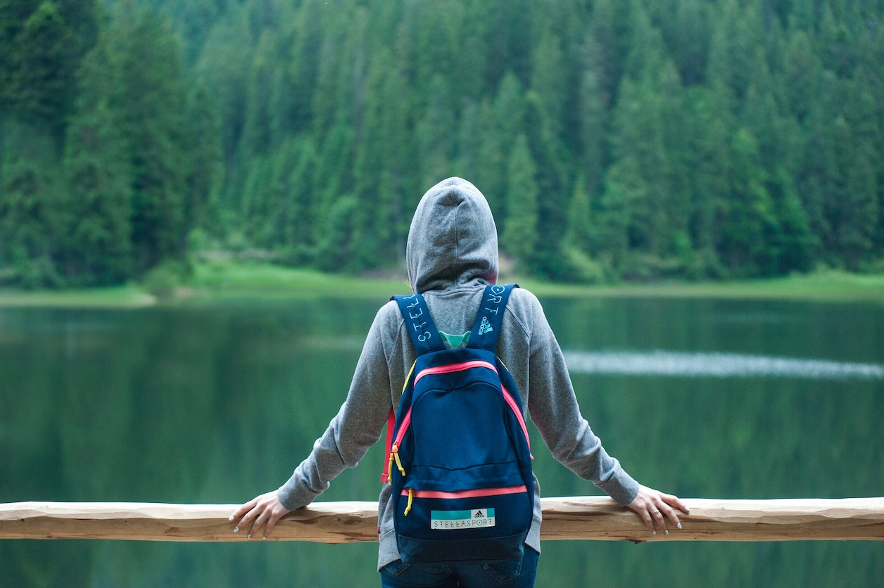 person standing on bridge with blue backpack