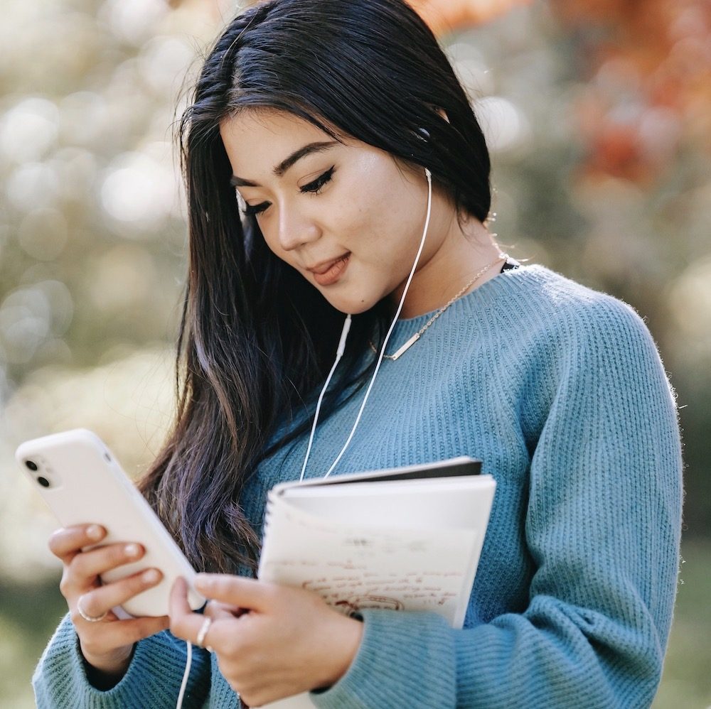 woman smiling while looking at her mobile phone